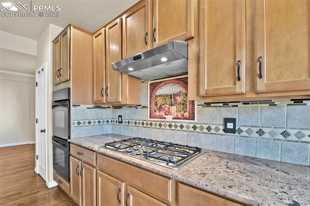 Image 13 of 50: Kitchen with under cabinet range hood, stainless steel gas cooktop, light w