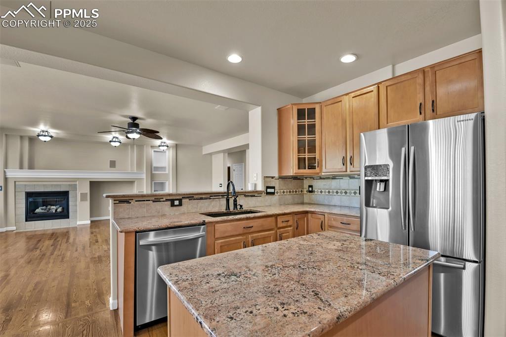Image 14 of 50: Kitchen featuring stainless steel appliances, a ceiling fan, light stone co