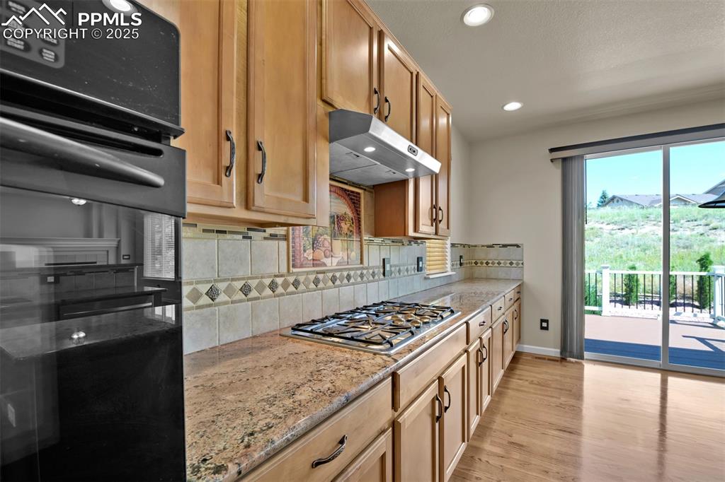 Image 16 of 50: Kitchen featuring stainless steel gas stovetop, under cabinet range hood, l