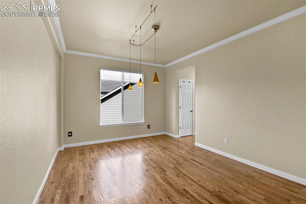 Image 21 of 50: Unfurnished dining area with wood finished floors and crown molding