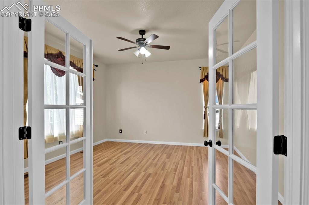 Image 23 of 50: Unfurnished room with french doors, a ceiling fan, and light wood-style flo