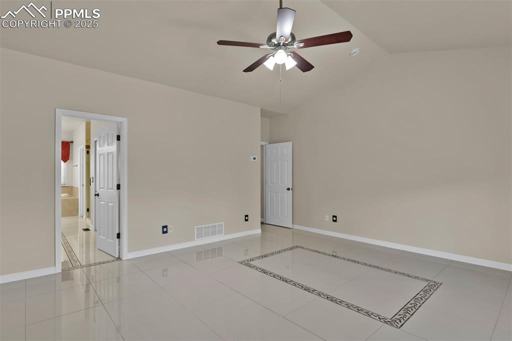 Image 25 of 50: Empty room featuring ceiling fan, lofted ceiling, and light tile patterned 
