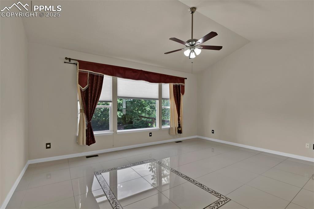 Image 26 of 50: Unfurnished room featuring lofted ceiling, ceiling fan, and light tile patt