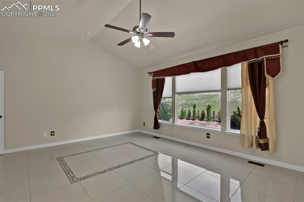 Image 27 of 50: Tiled empty room featuring lofted ceiling and a ceiling fan