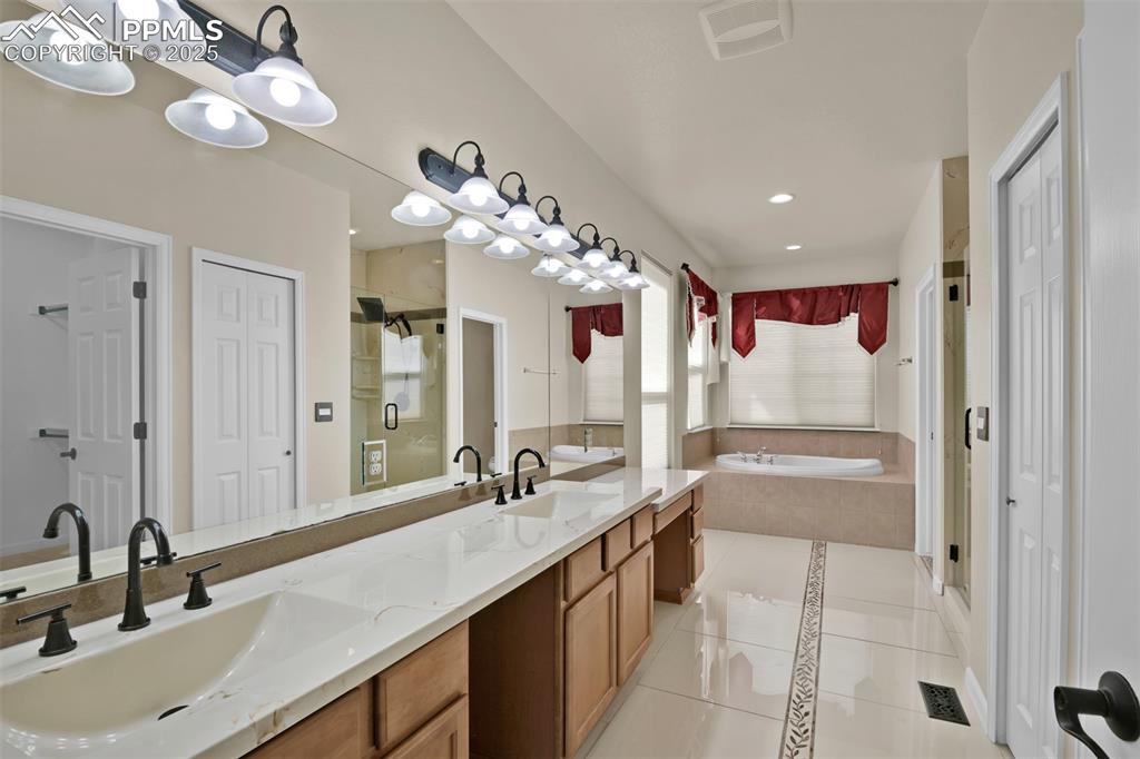 Image 28 of 50: Bathroom featuring a closet, tile patterned floors, a garden tub, double va