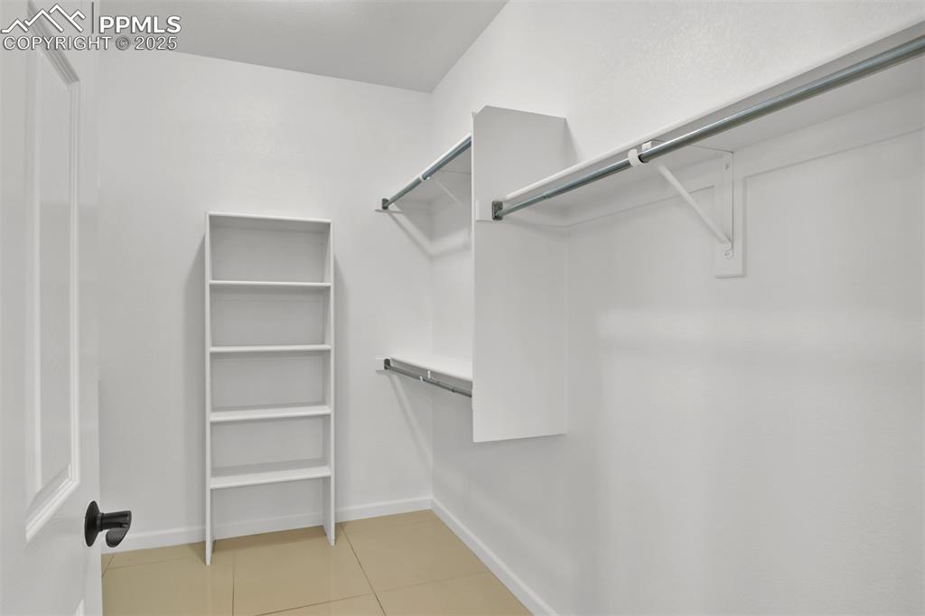 Image 30 of 50: Walk in closet with light tile patterned floors