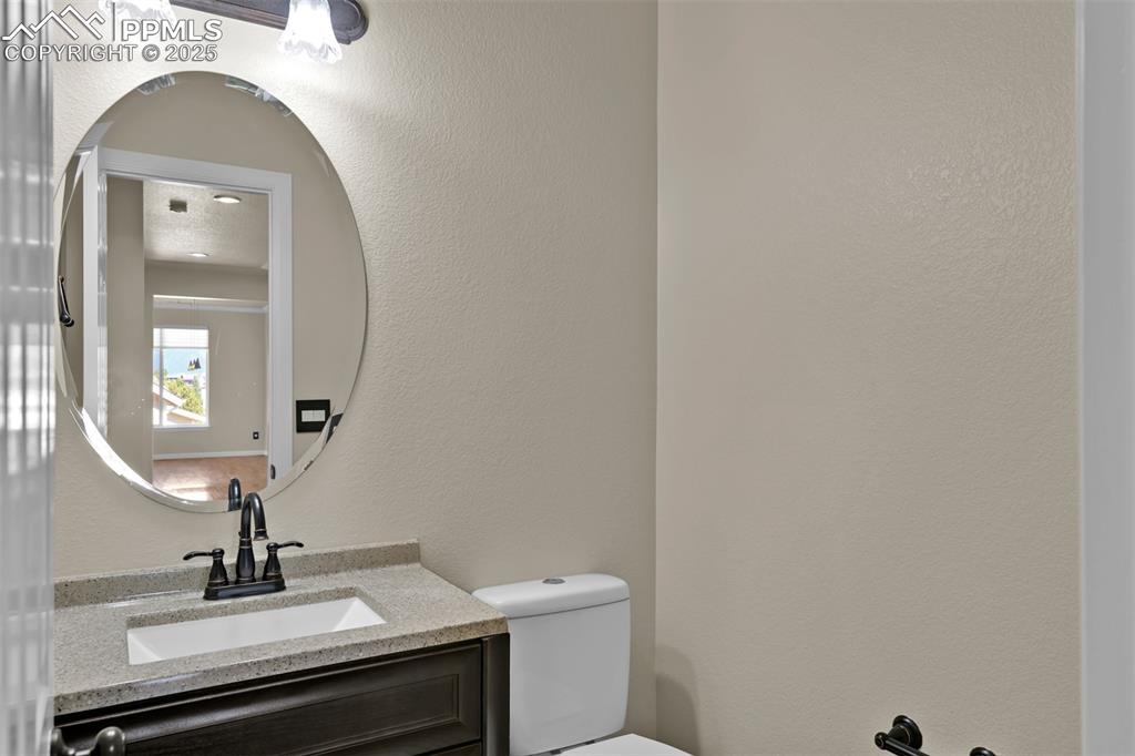 Image 32 of 50: Half bathroom featuring vanity and a textured wall