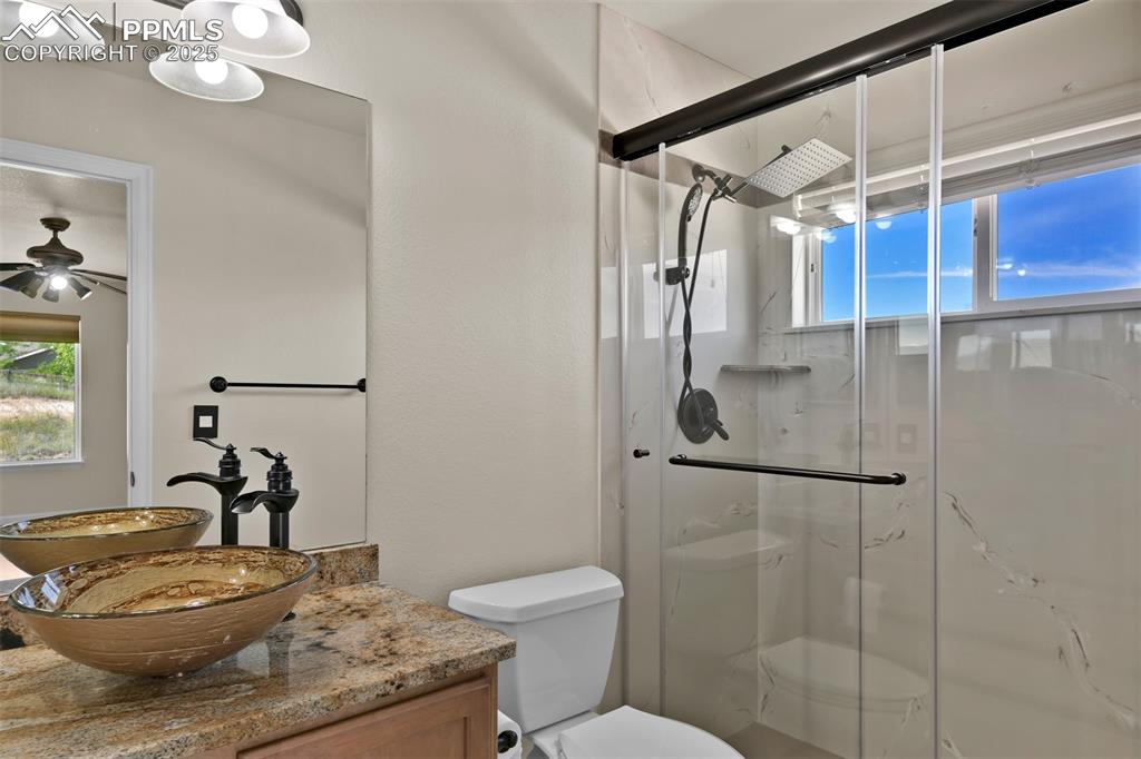 Image 38 of 50: Bathroom featuring a marble finish shower, vanity, and a ceiling fan