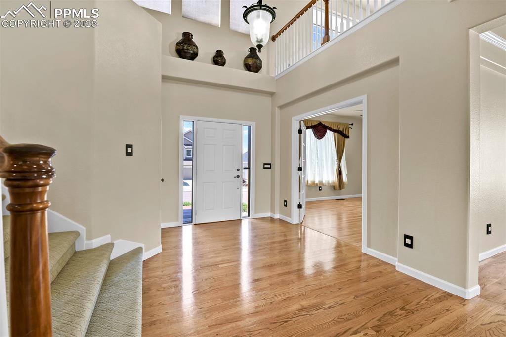 Image 8 of 50: Entryway with light wood-style flooring, a high ceiling, and stairway
