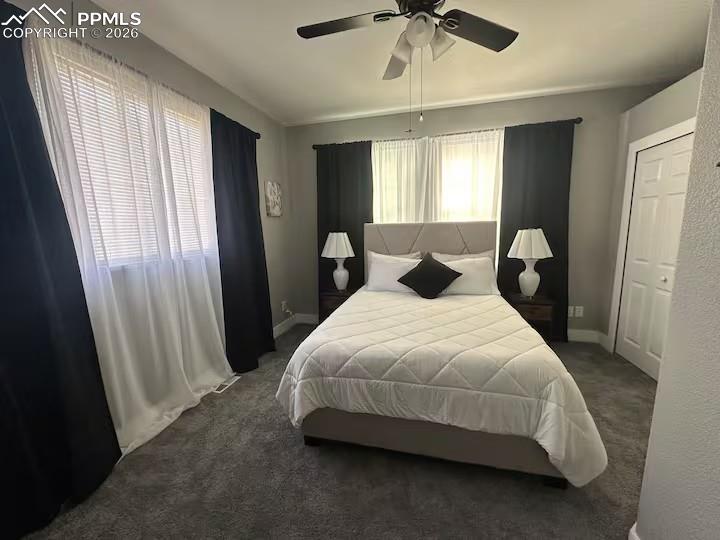 Image 11 of 23: Bedroom with dark colored carpet and a ceiling fan