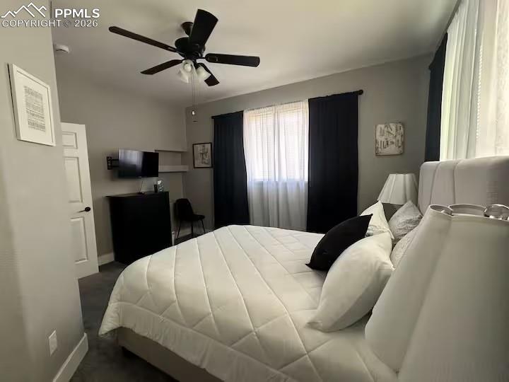 Image 12 of 23: Bedroom with ceiling fan and dark colored carpet