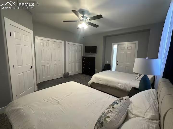 Image 13 of 23: Bedroom featuring multiple closets, a ceiling fan, and dark colored carpet