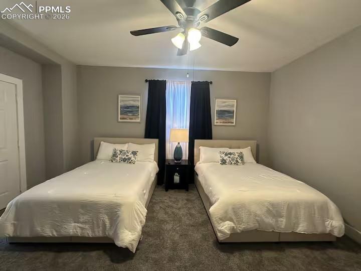 Image 15 of 23: Bedroom with dark colored carpet and a ceiling fan