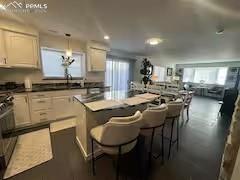 Image 2 of 10: Kitchen featuring a center island, hanging light fixtures, dark countertops