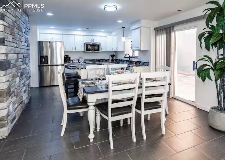 Image 3 of 10: Dining area featuring dark tile patterned floors and recessed lighting