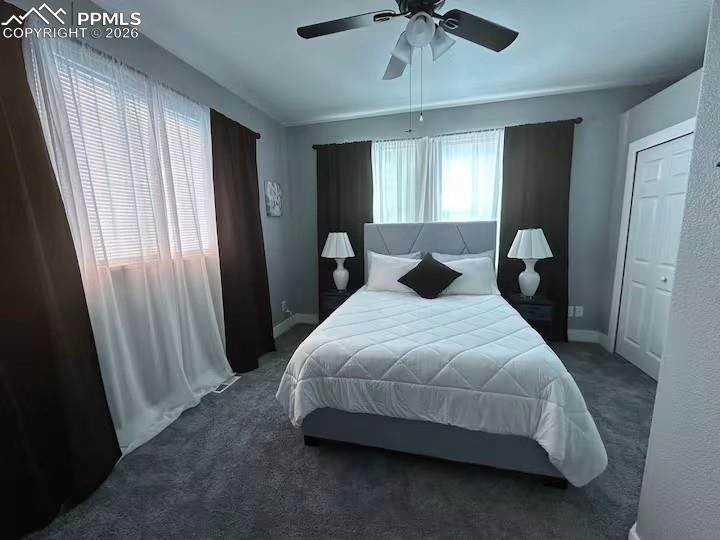 Image 6 of 10: Bedroom with dark carpet, a ceiling fan, and a closet