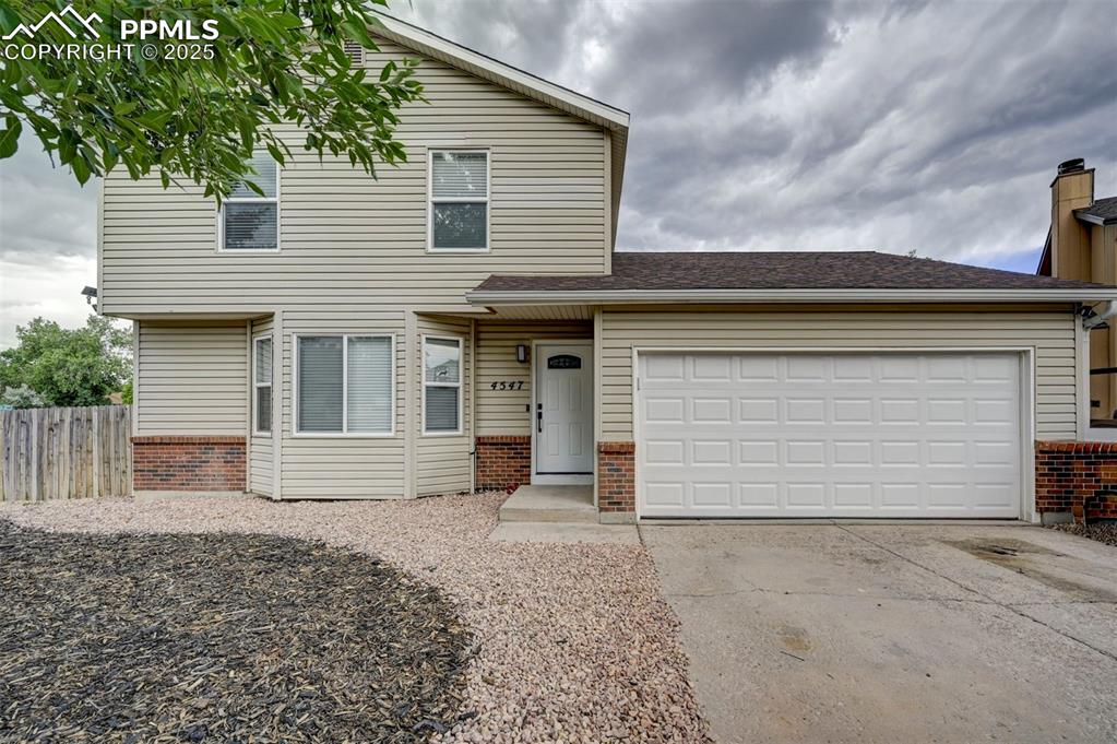 Caption: Traditional home featuring brick siding, concrete driveway, and a garage