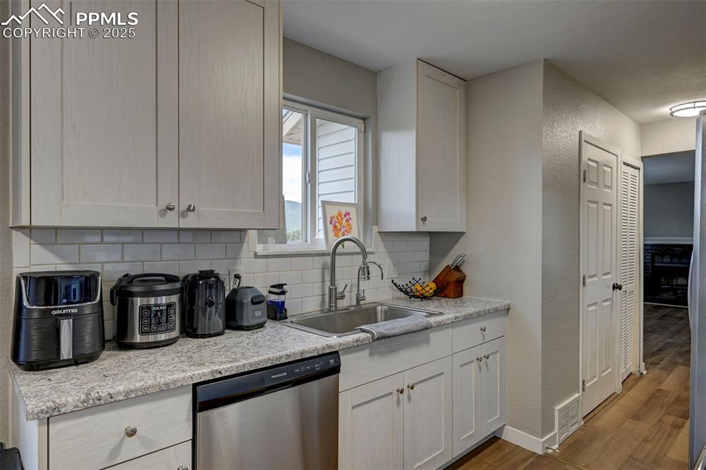 Image 10 of 33: Kitchen with dishwasher, decorative backsplash, wood finished floors, white