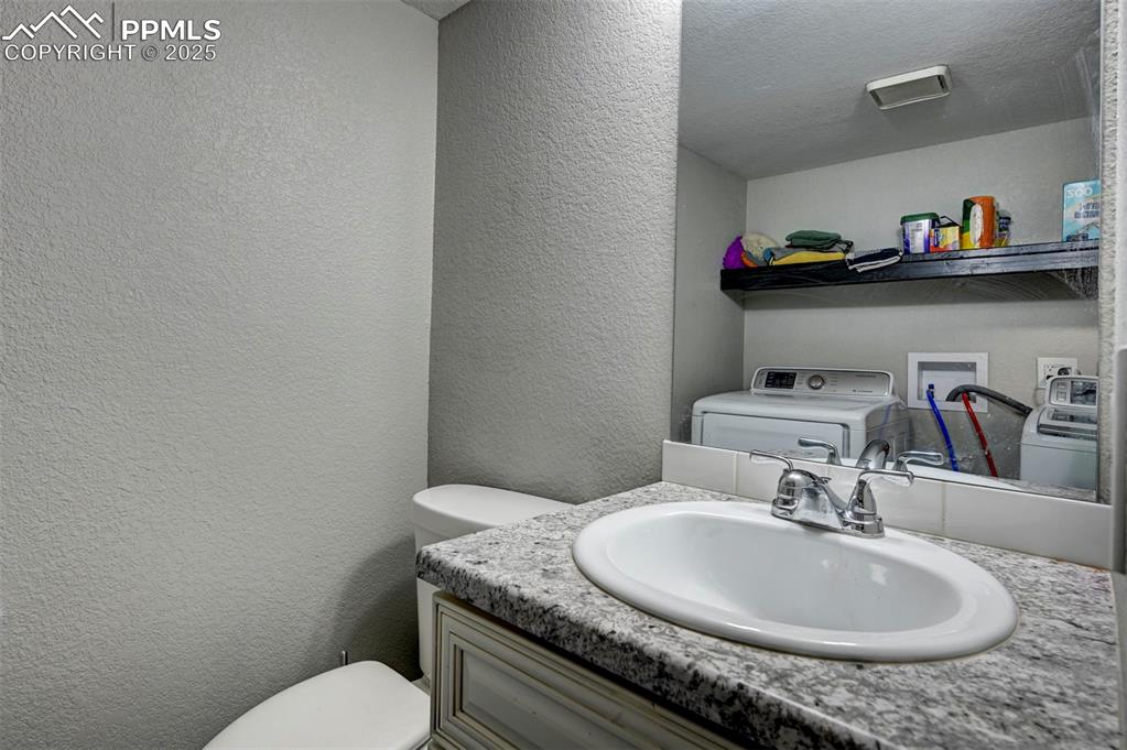 Image 12 of 33: Bathroom with a textured wall, vanity, and washer and dryer