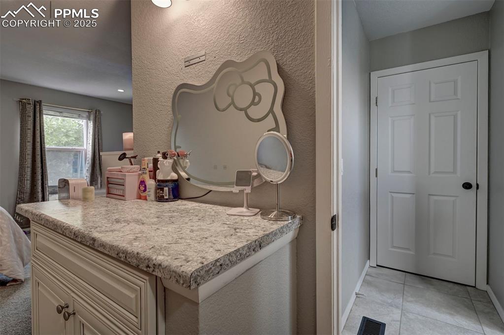 Image 14 of 33: Kitchen with a textured wall, light countertops, light tile patterned floor