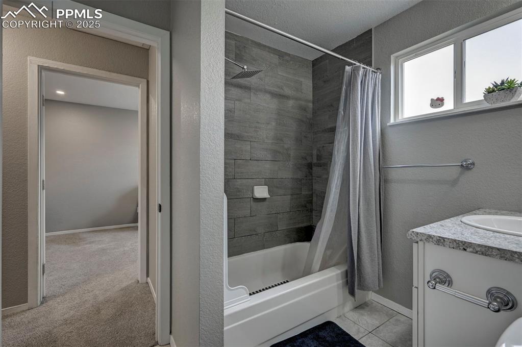Image 16 of 33: Bathroom with shower / bath combo with shower curtain and vanity