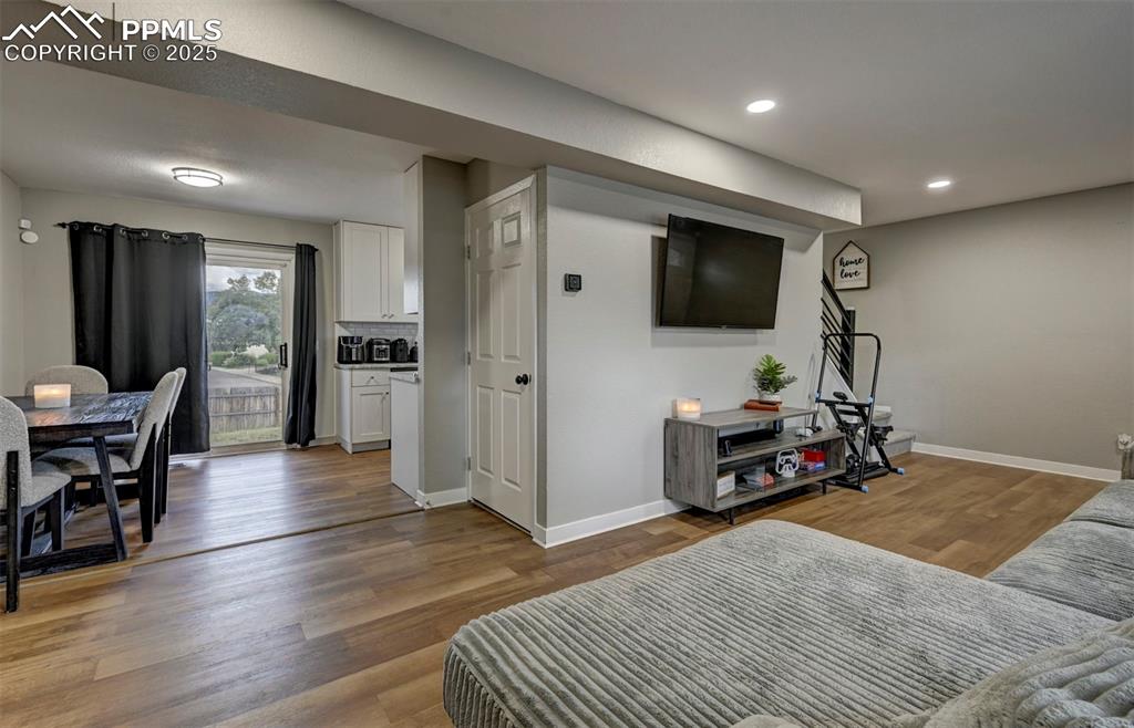 Image 19 of 33: Living area with light wood-style flooring and recessed lighting