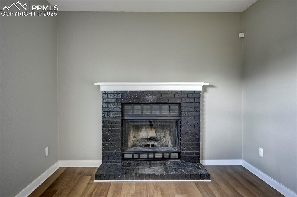 Image 25 of 33: Detailed view of wood finished floors and a brick fireplace