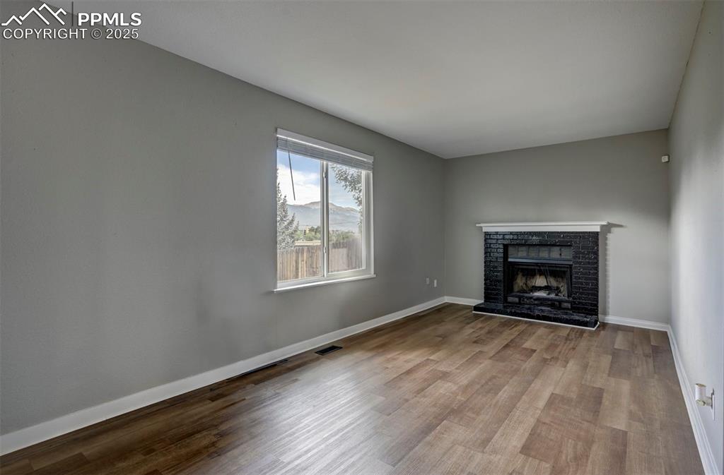 Image 26 of 33: Unfurnished living room featuring wood finished floors and a fireplace with
