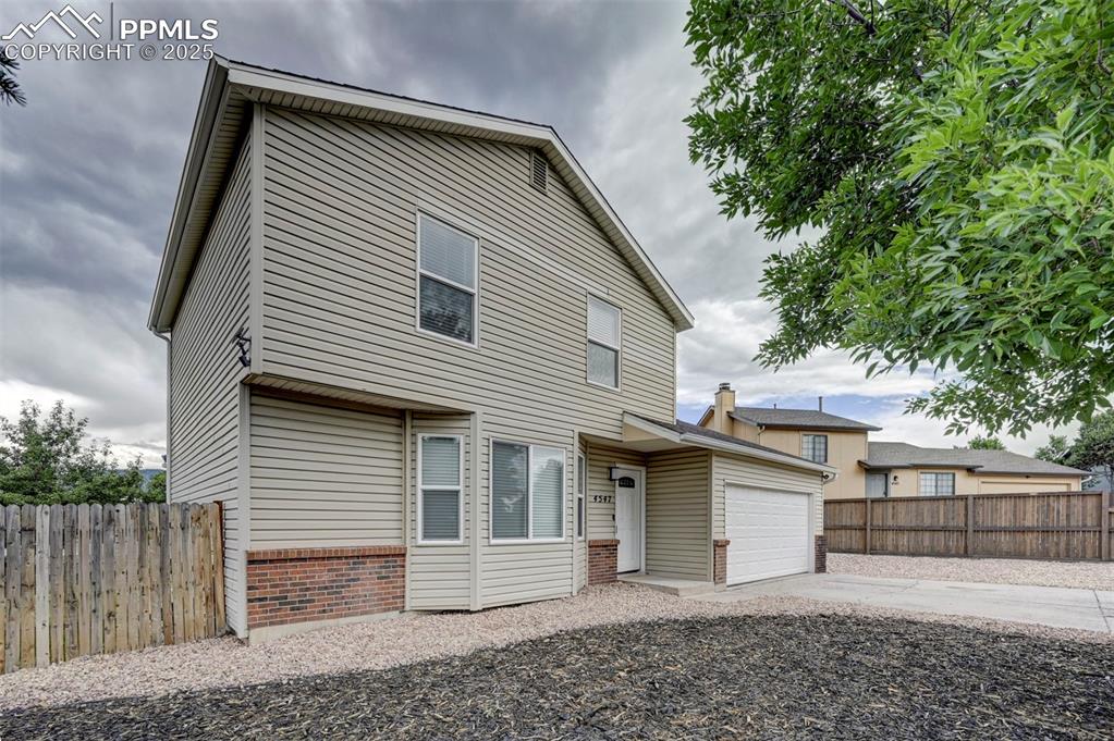 Image 3 of 33: View of front of property with an attached garage, concrete driveway, and b
