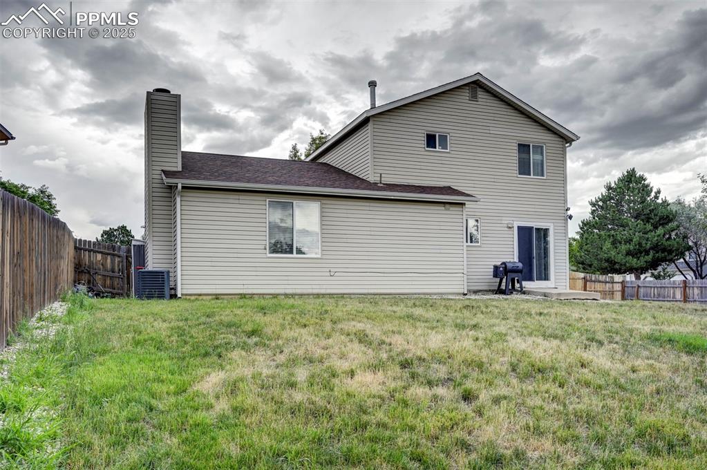 Image 30 of 33: Rear view of property with a fenced backyard and a chimney