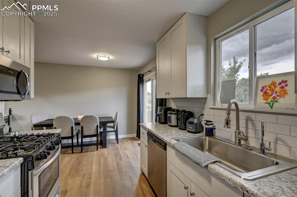 Image 8 of 33: Kitchen featuring stainless steel appliances, decorative backsplash, light