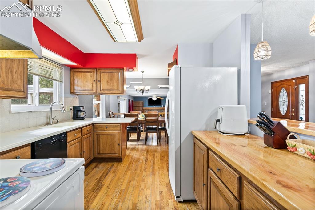Image 11 of 36: Kitchen featuring brown cabinetry, pendant lighting, and white appliances