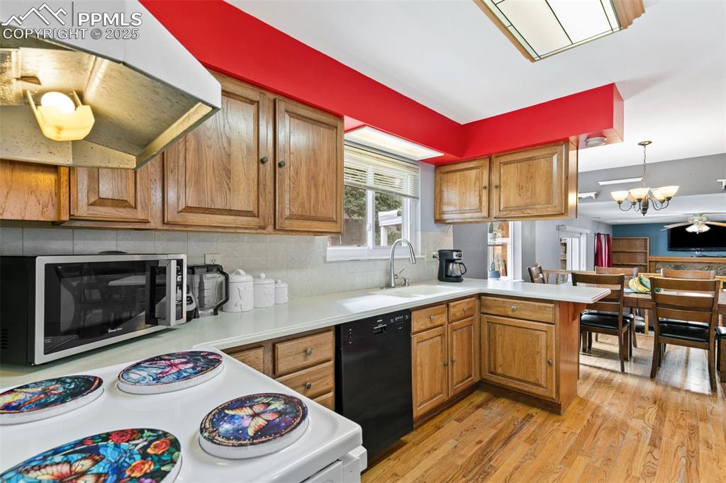 Image 12 of 36: Kitchen featuring brown cabinets, stainless steel microwave, range hood, bl