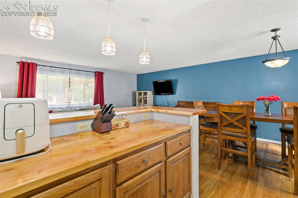 Image 14 of 36: Kitchen with pendant lighting, light wood-style floors, wooden counters, br