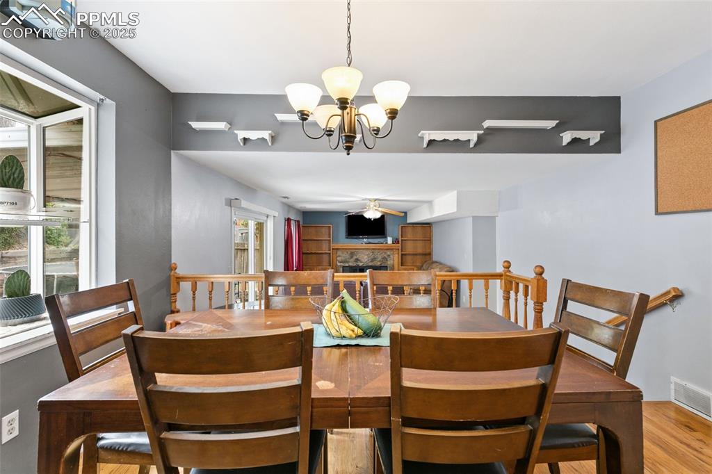 Image 15 of 36: Dining area featuring a fireplace, light wood-style flooring, and a chandel