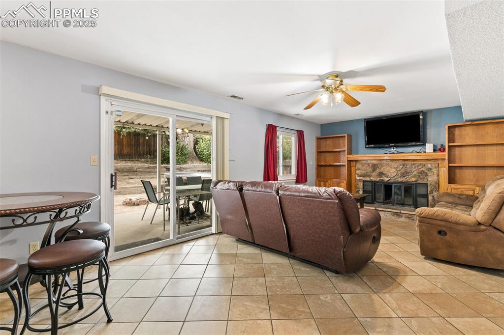 Image 18 of 36: Living room featuring a stone fireplace, light tile patterned floors, and a