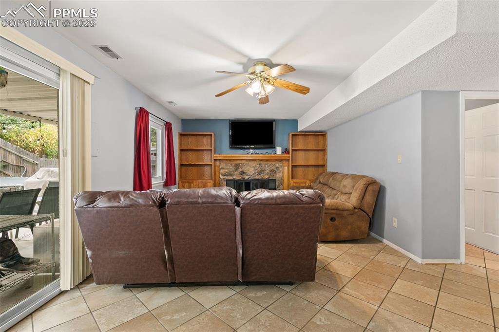 Image 19 of 36: Living area featuring a stone fireplace, light tile patterned floors, and a