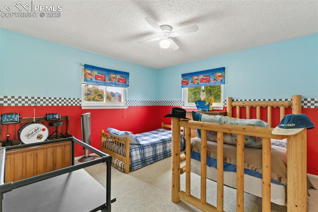 Image 26 of 36: Bedroom with light colored carpet, a textured ceiling, and a ceiling fan