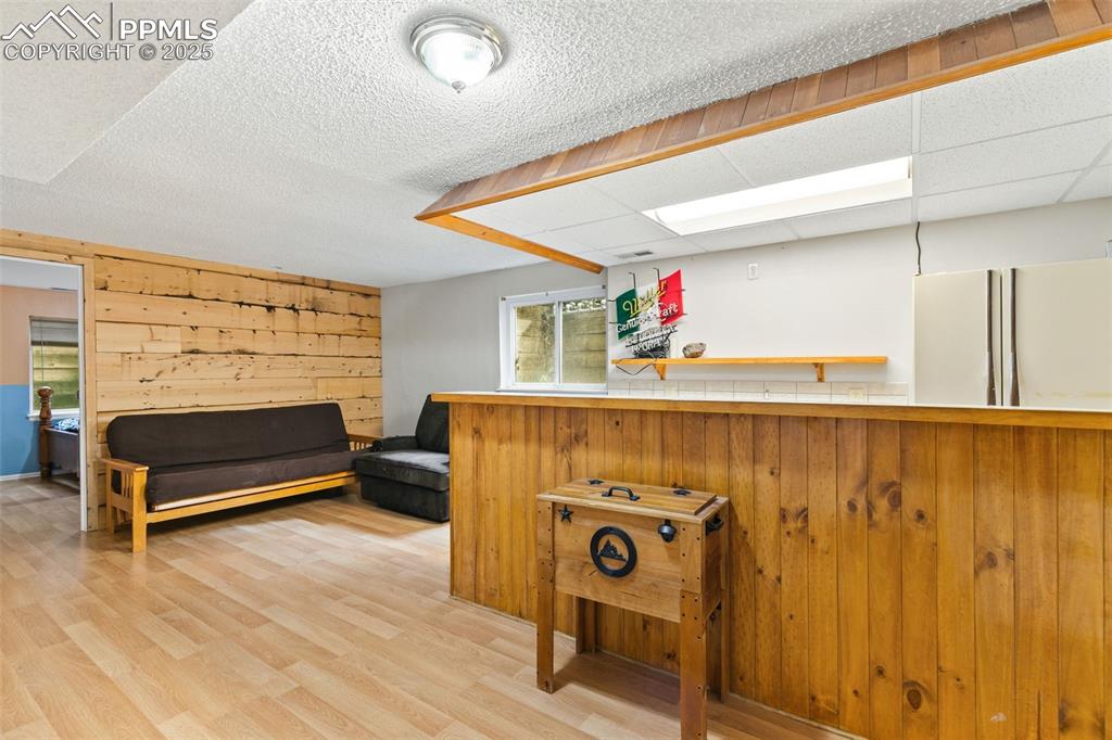 Image 28 of 36: Bar with wooden walls, light wood finished floors, open shelves, and freest