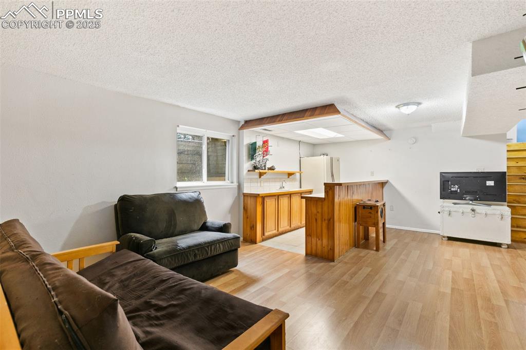 Image 29 of 36: Living area with light wood-style flooring and a textured ceiling
