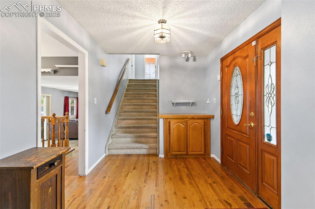 Image 4 of 36: Entrance foyer with light wood-style floors, stairway, and a textured ceili