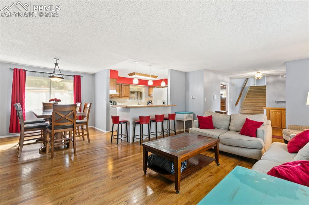 Image 5 of 36: Living room featuring light wood-style floors, stairs, and a textured ceili