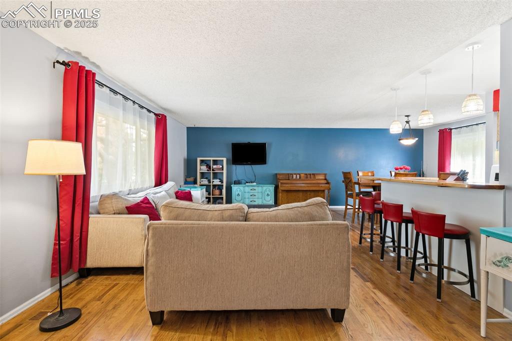 Image 7 of 36: Living area featuring a textured ceiling, light wood-style flooring, and pl