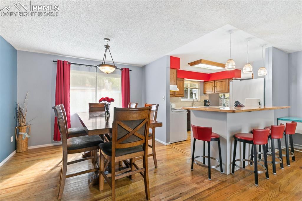 Image 8 of 36: Dining room featuring light wood-type flooring and a textured ceiling