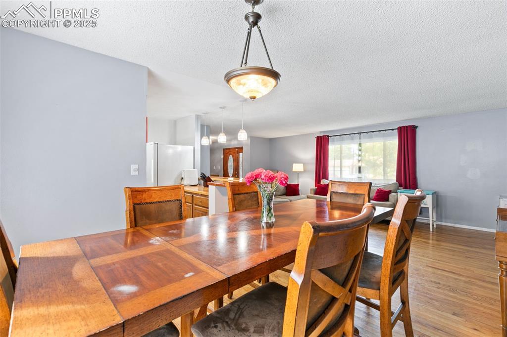 Image 9 of 36: Dining area with light wood-type flooring and a textured ceiling
