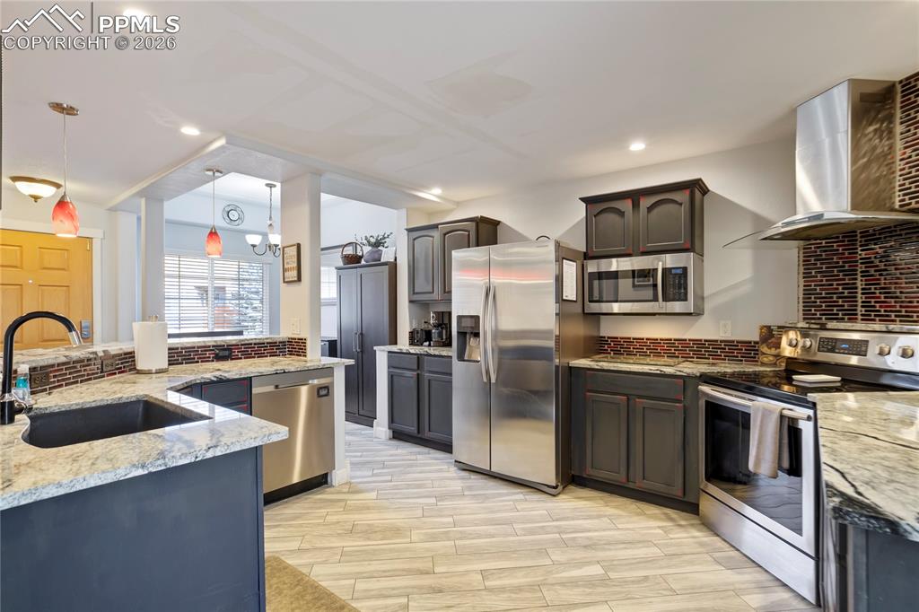 Image 10 of 42: Kitchen featuring stainless steel appliances, light stone counters, backspl
