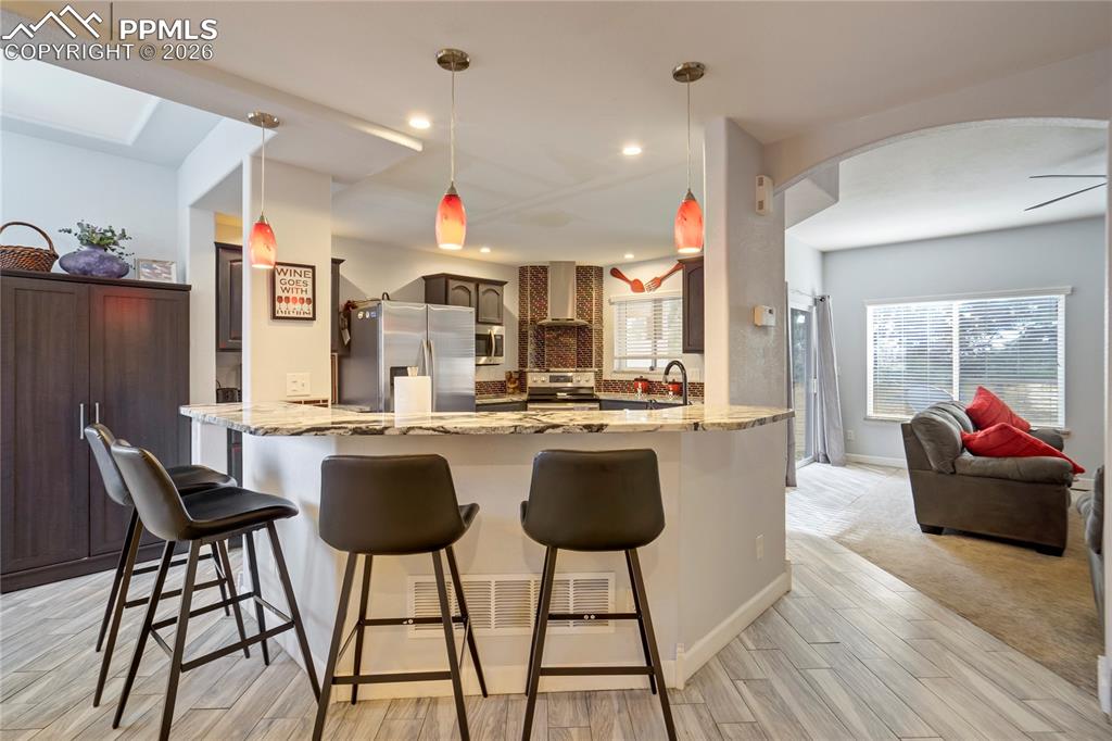 Image 11 of 42: Kitchen with arched walkways, decorative light fixtures, stainless steel ap