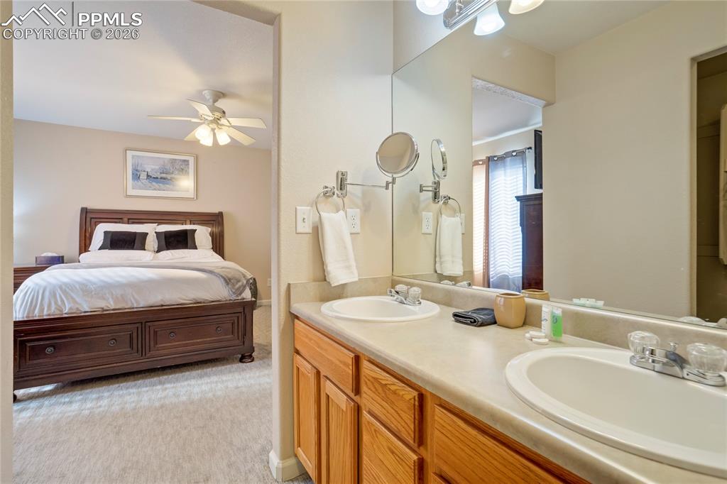 Image 21 of 42: Full bathroom with double vanity, ensuite bath, and ceiling fan
