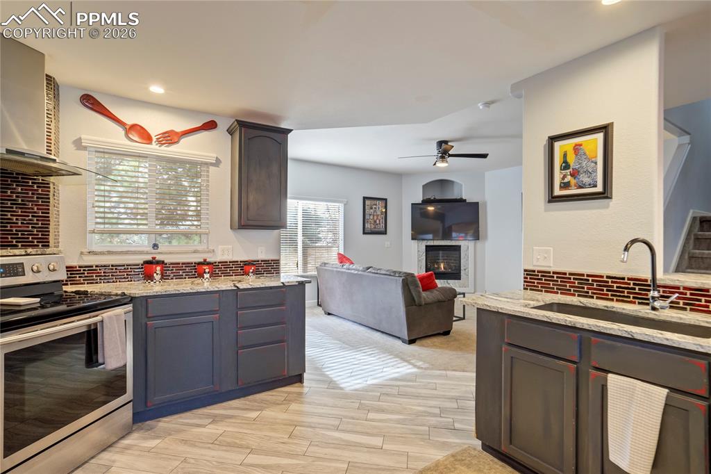 Image 3 of 42: Kitchen with stainless steel range with electric cooktop, backsplash, light