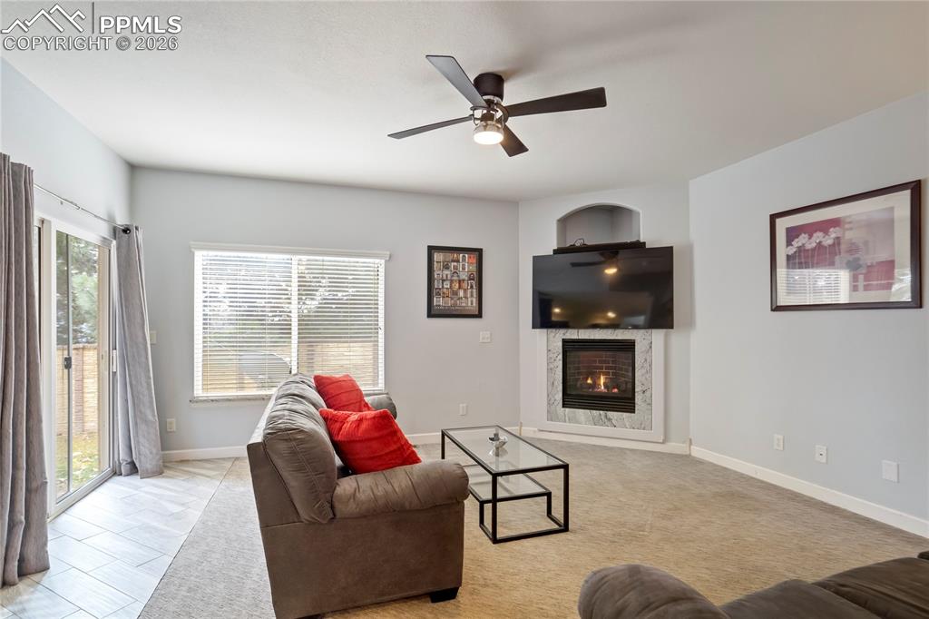 Image 4 of 42: Living area featuring a fireplace and ceiling fan